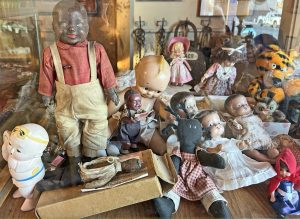 Photo of a display of various antique dolls, including one KEWPIE doll.